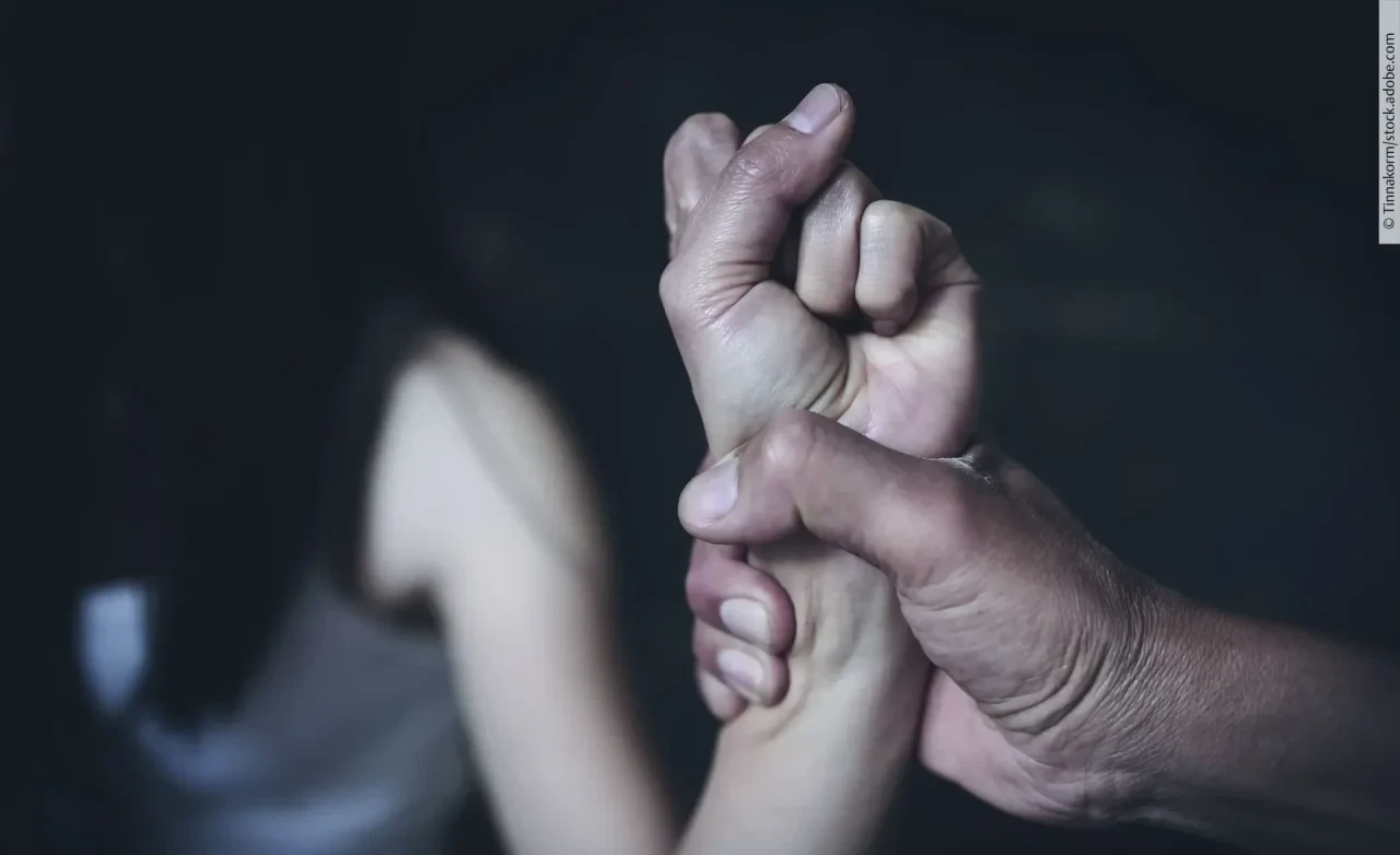 Häusliche Gewalt. Mann hält andere Hand fest.