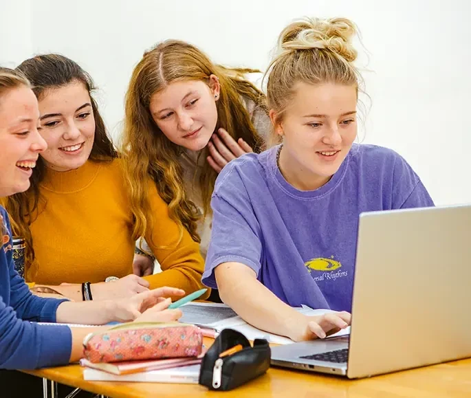 Schülerinnen sitzen vor Laptop