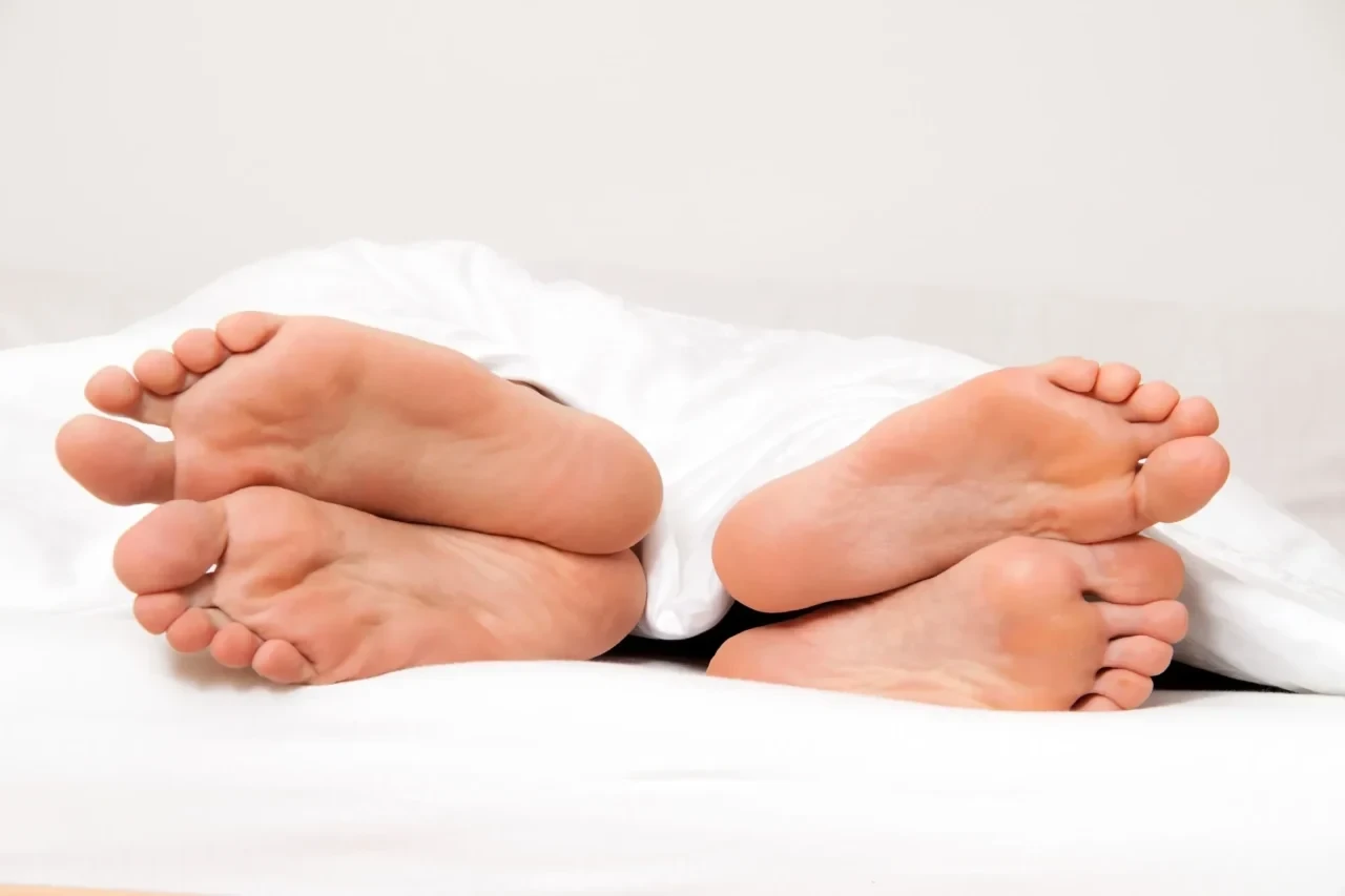 2 paar Füße im Bett zeigen voneinander weg